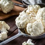 Fresh organic cauliflower in an old metal filter pot photographed on a rustic wooden table. This vegetable is considered a healthy salad topping. The main colors are white and brown. Low-key DSRL studio photo taken with Canon EOS 5D Mk II and Canon EF 100mm f/2.8L Macro IS USM